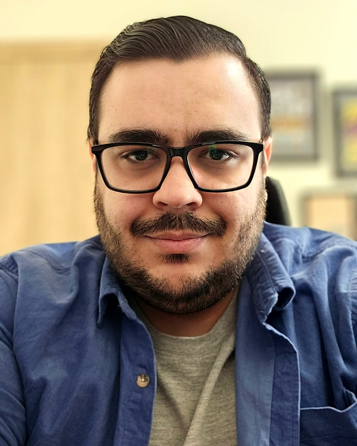 Bahman Shadmehr, wearing glasses and a denim shirt, at his desk