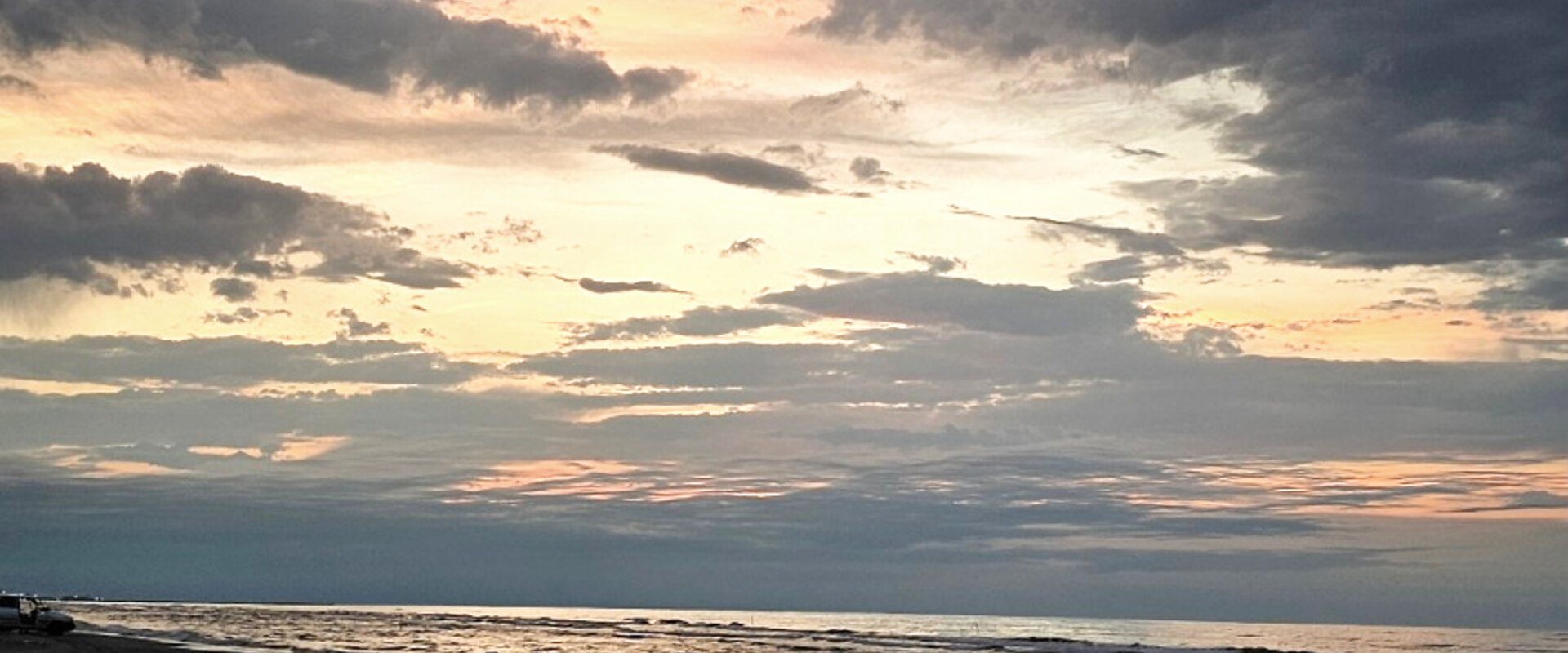 A pastel sky over a calm beach at dusk